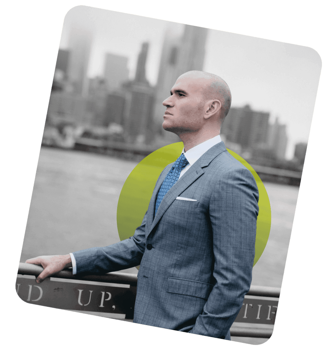 Michael Fabiano in a suit on the Brooklyn waterfront, the Manhattan skyline behind him